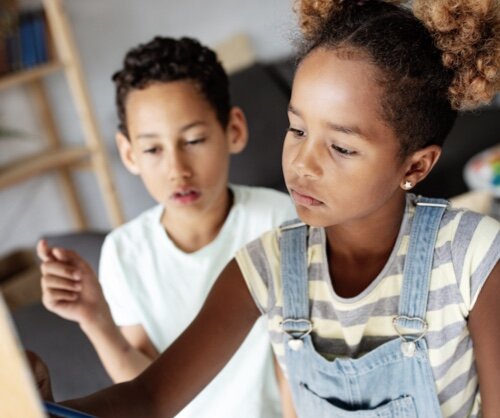 Kinder beim kreativen Malen Zwei Kinder arbeiten gemeinsam an einem Projekt. Ein Mädchen mit lockigem Haar konzentriert sich auf eine Aufgabe, während ein Junge im Hintergrund zuschaut.