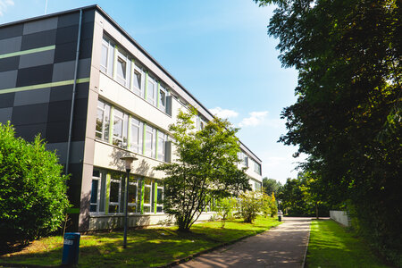 Moderne Architektur im Grünen Ansicht des Schulgebäudes der Grund- und Stadtteilschule Altrahlstedt mit angrünenden Bäumen und einem Gehweg.